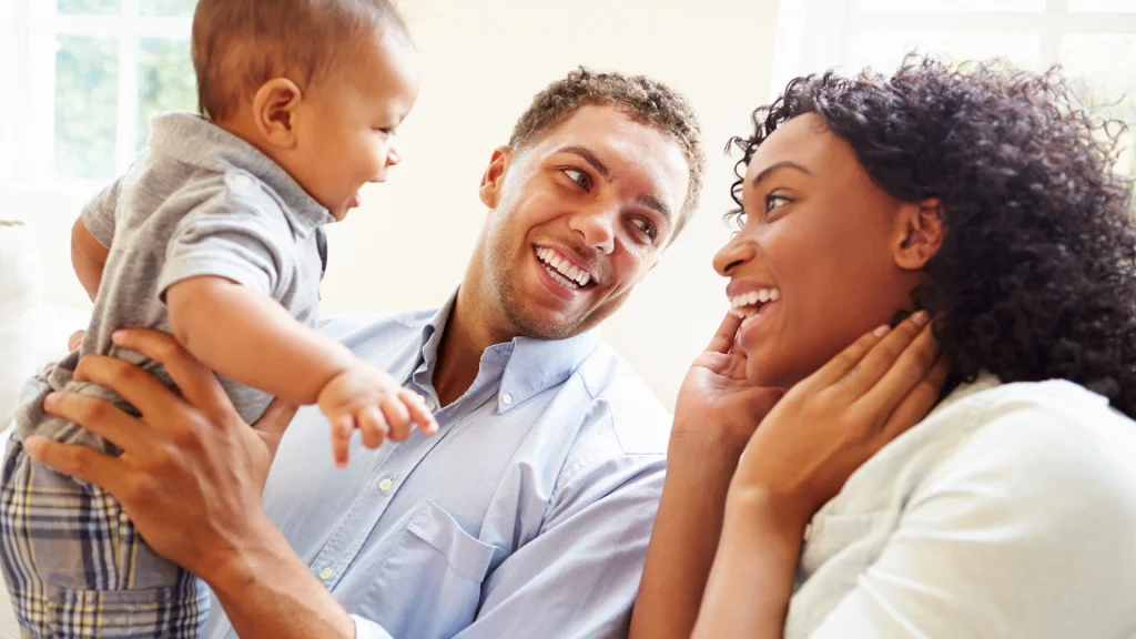 mom and dad happily holding baby