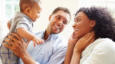 mom and dad happily holding baby