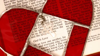 bible opened with a red glass heart layered over scripture